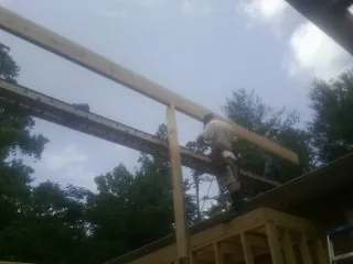 Carpenter setting a ridge beam over a new addition frame — Ice Dam Removal by Roofing Brothers in Limington