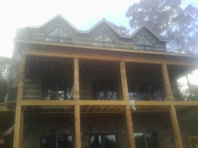 Dormers and porch framing on a large log home under construction — Roof Coating work by our crew in Limington