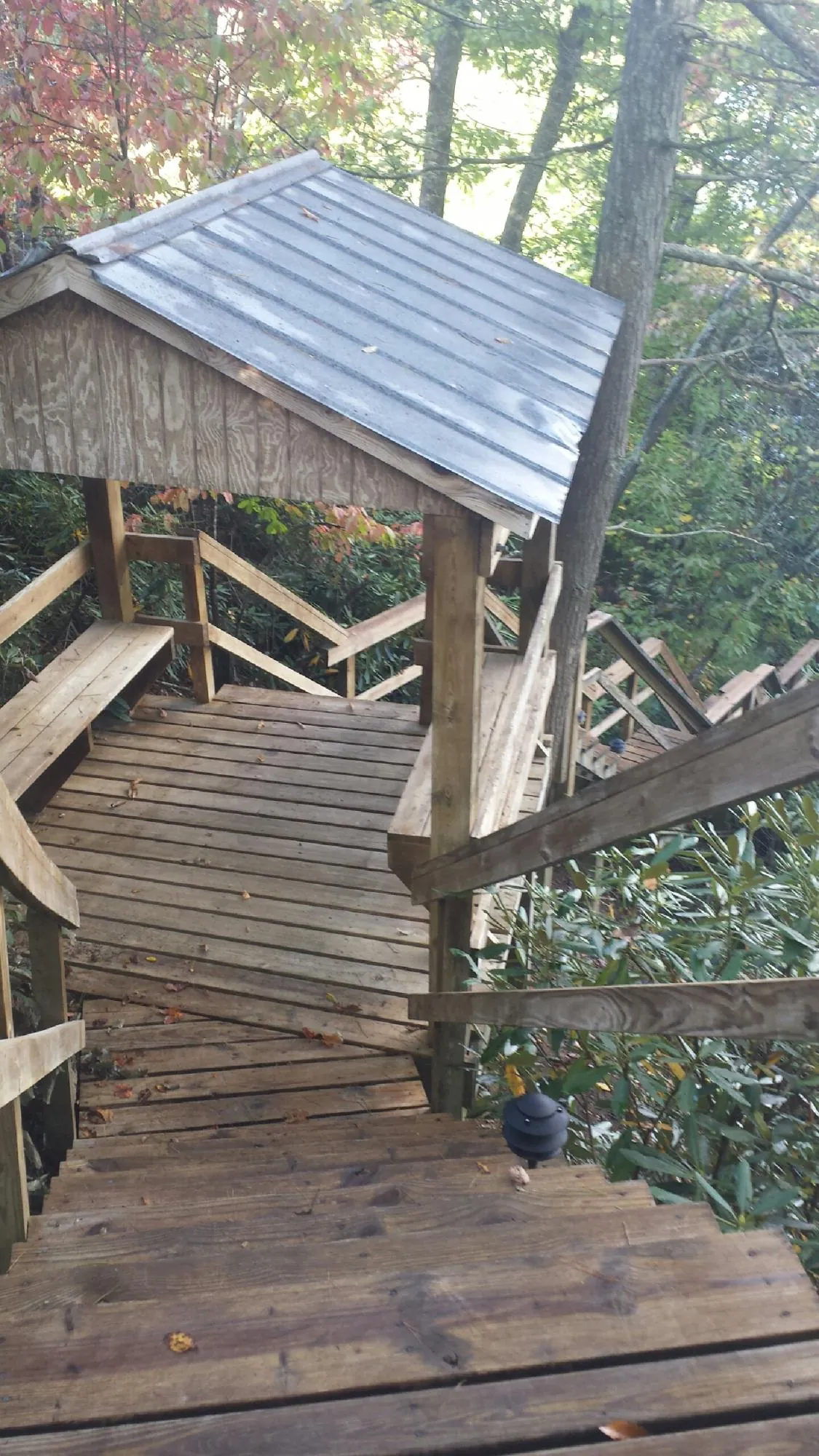 Metal roofed shelter over wooden steps on a wooded walkway — Skylight Repair & Installation work by our crew in Limington