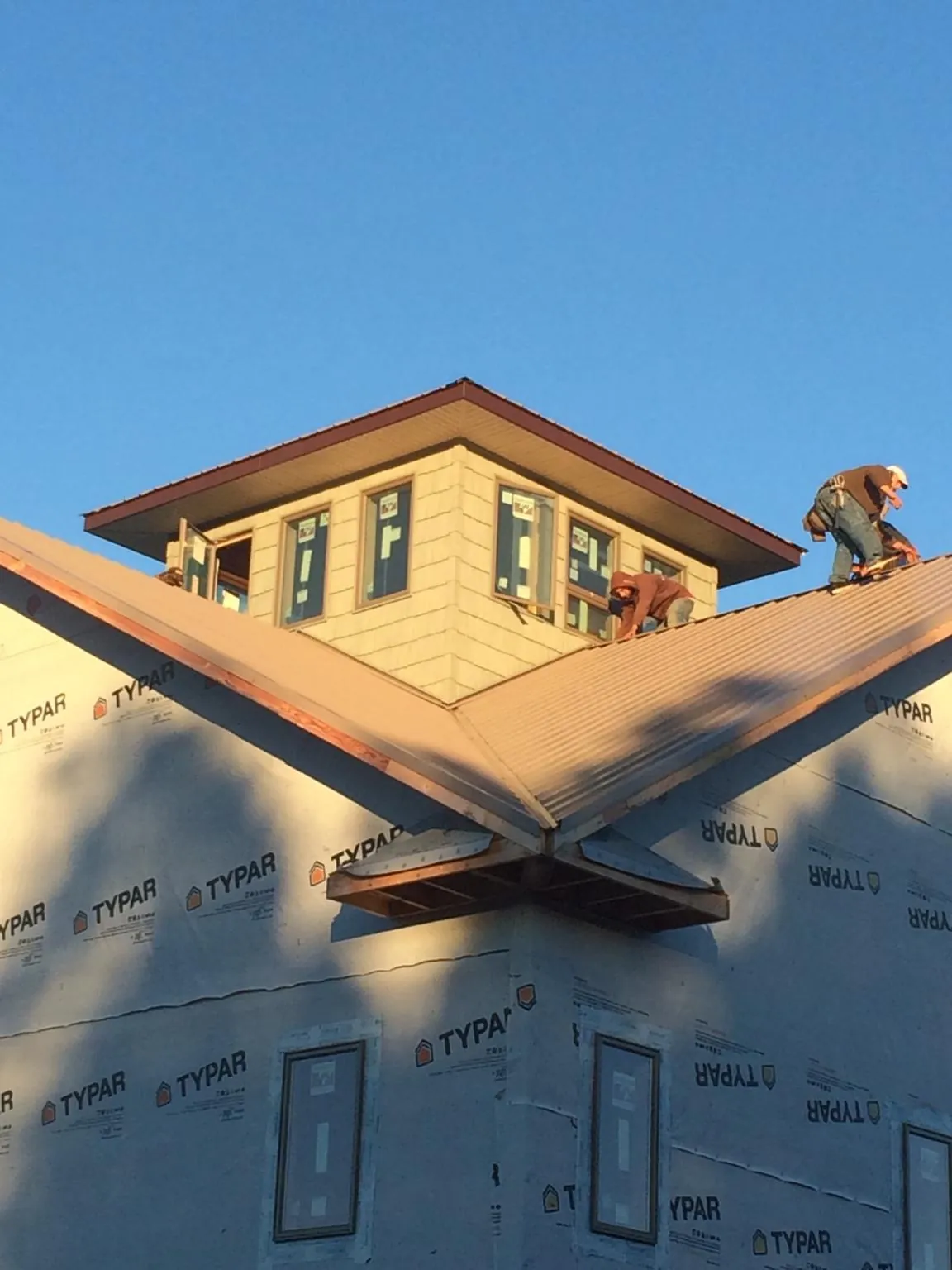 Roofers working around a rooftop cupola on a new metal roof at sunset — Roof Waterproofing in Limington by Roofing Brothers